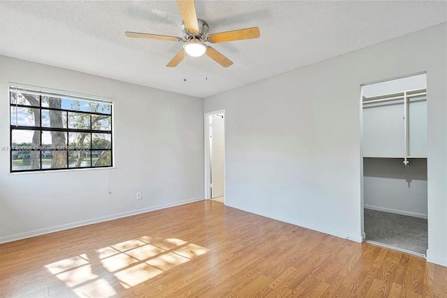 unfurnished bedroom with light wood finished floors, a closet, ceiling fan, a textured ceiling, and baseboards