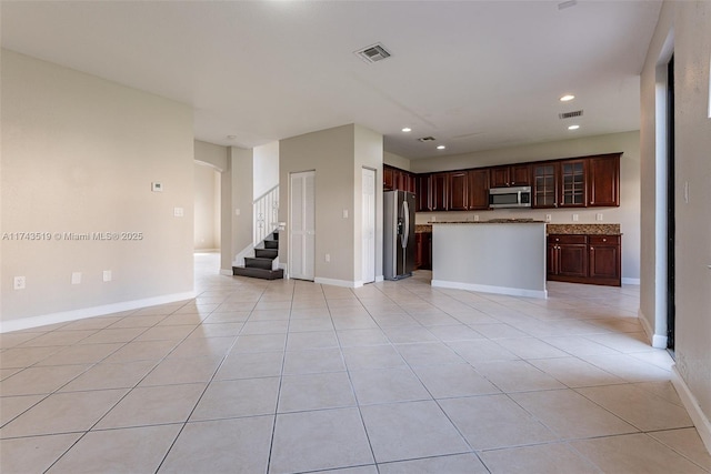 kitchen featuring light tile patterned floors, dark brown cabinets, stainless steel appliances, and a center island