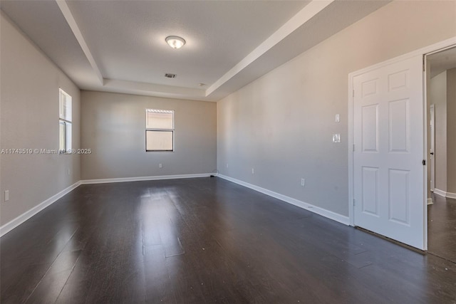 unfurnished room with a raised ceiling and dark hardwood / wood-style floors