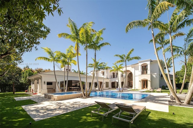 rear view of property with a patio, a lawn, and a pool with hot tub