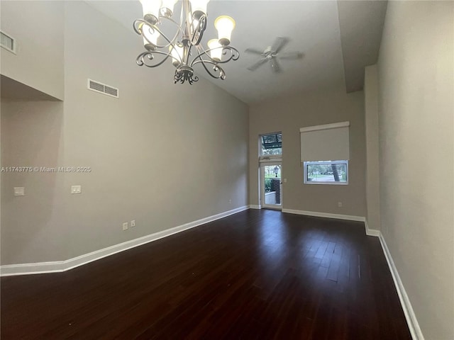 spare room featuring dark hardwood / wood-style flooring, high vaulted ceiling, and a chandelier