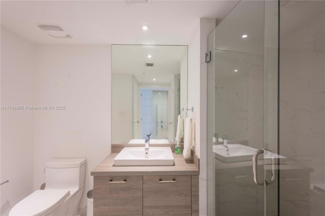 bathroom featuring a shower with door, vanity, and toilet