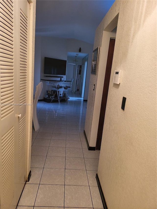 hallway with lofted ceiling and light tile patterned floors