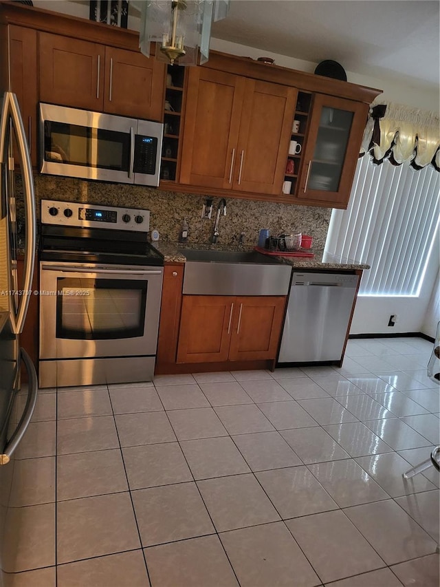 kitchen featuring light tile patterned flooring, sink, decorative backsplash, dark stone counters, and stainless steel appliances