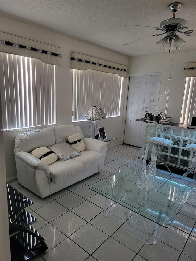 living room with tile patterned flooring, ceiling fan, and a textured ceiling