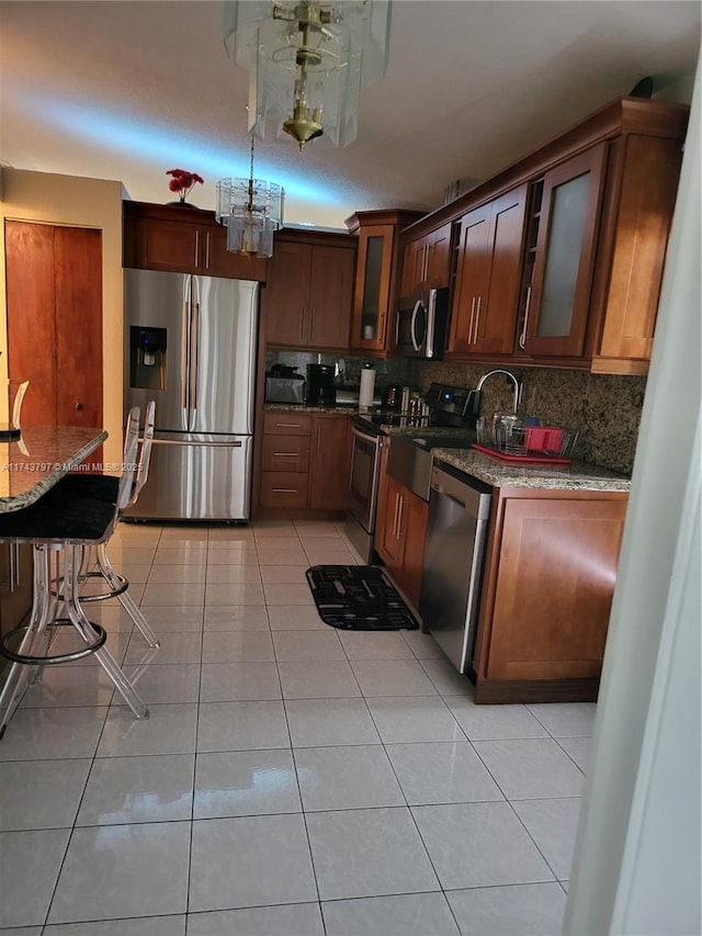 kitchen with stainless steel appliances, light tile patterned floors, backsplash, and dark stone counters