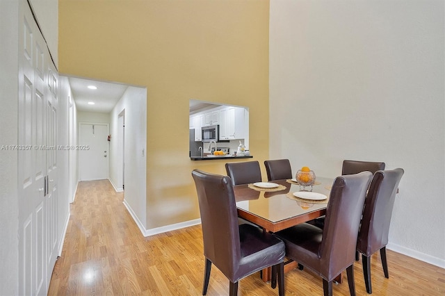 dining space with a towering ceiling and light wood-type flooring