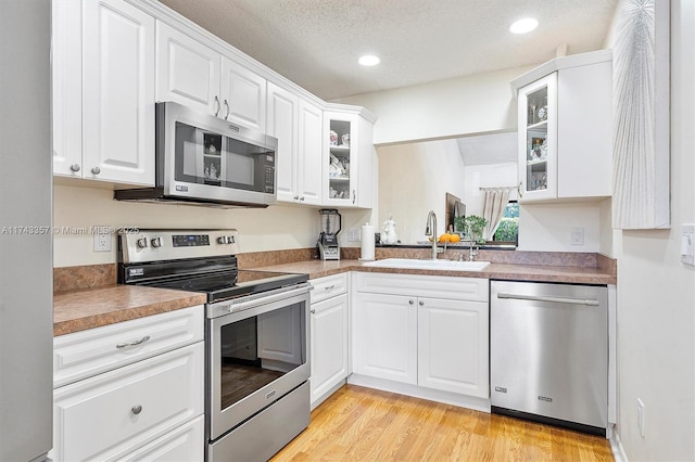4149 S Pine Island Rd, Davie, FL 33328 - kitchen with stainless steel appliances, glass insert cabinets, white cabinets, light wood-style floors, and recessed lighting