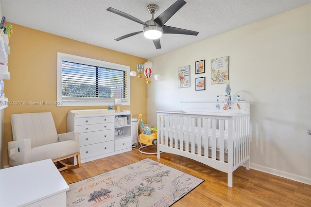 4149 S Pine Island Rd, Davie, FL 33328 - bedroom featuring wood finished floors, a nursery area, a ceiling fan, and a textured ceiling