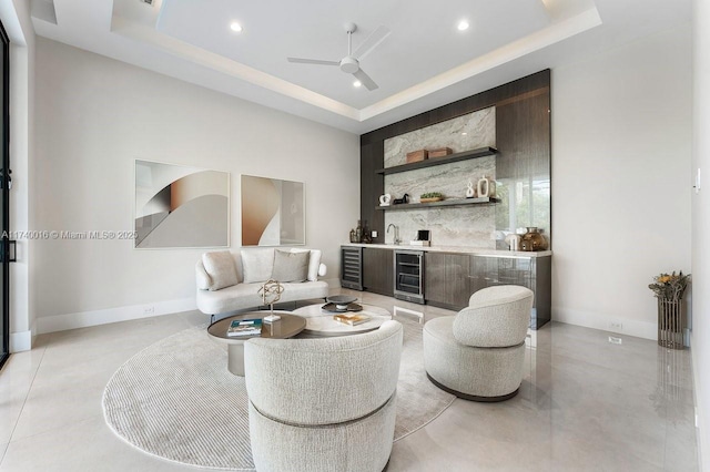 living room with wine cooler, bar area, and a raised ceiling