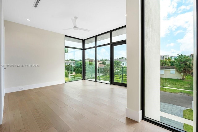 unfurnished room featuring a wall of windows, light hardwood / wood-style floors, and ceiling fan