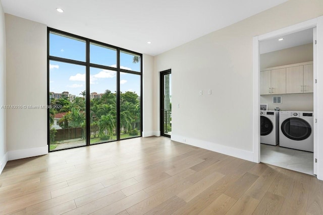 unfurnished room with floor to ceiling windows, washer and dryer, and light wood-type flooring