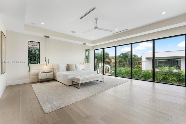 unfurnished bedroom with ceiling fan, a raised ceiling, and light hardwood / wood-style flooring