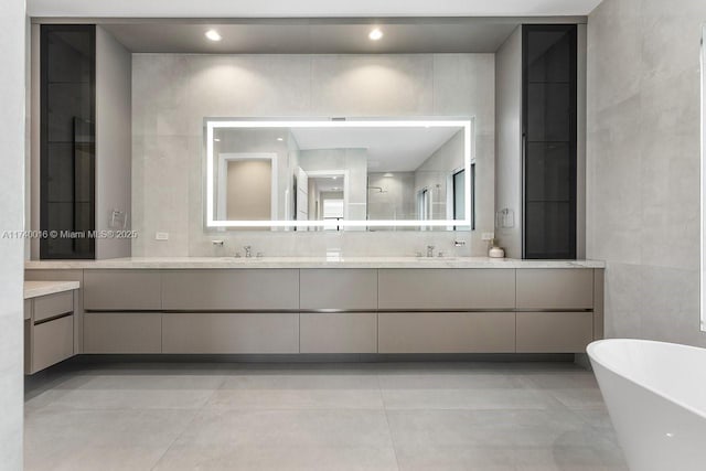 bathroom featuring tile patterned flooring, vanity, tile walls, and a tub to relax in