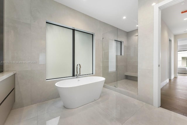 bathroom featuring plus walk in shower, tile walls, and tile patterned floors