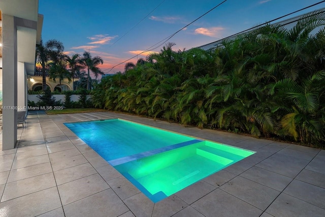 pool at dusk featuring a patio