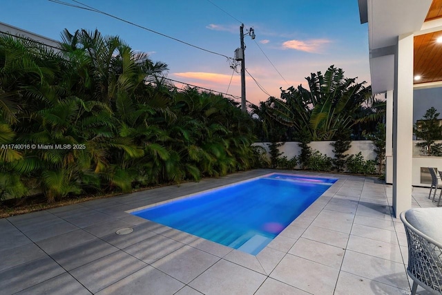 pool at dusk with a patio area