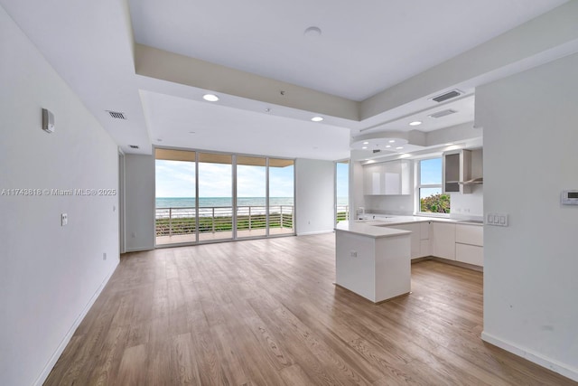 kitchen featuring a water view, expansive windows, light wood-type flooring, and white cabinets