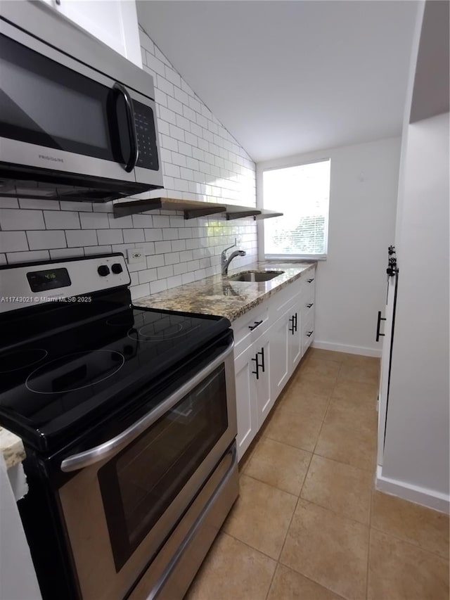 kitchen with stainless steel appliances, tasteful backsplash, white cabinetry, a sink, and light stone countertops