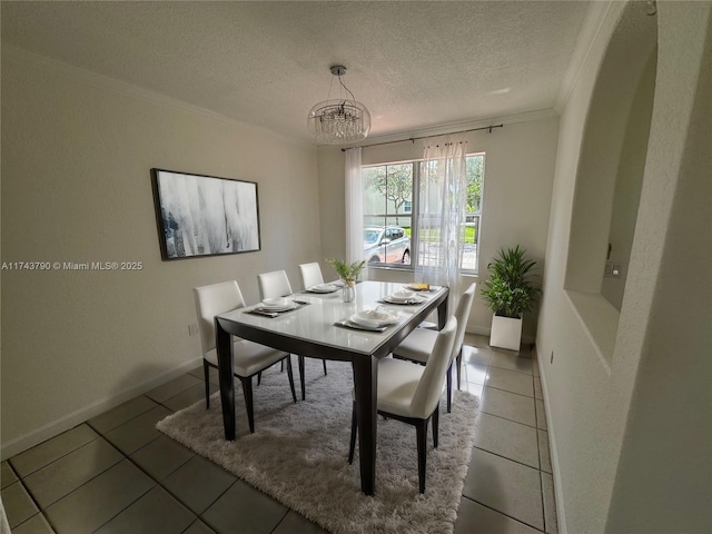 tiled dining room featuring a notable chandelier, ornamental molding, and a textured ceiling