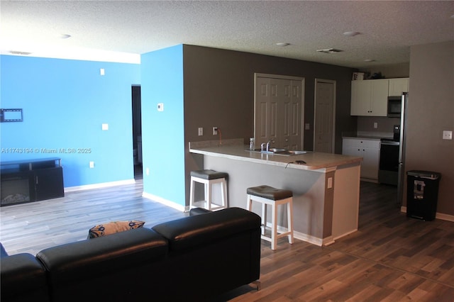 kitchen with appliances with stainless steel finishes, a breakfast bar, sink, white cabinetry, and kitchen peninsula