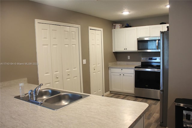 kitchen featuring white cabinetry, dark wood-type flooring, appliances with stainless steel finishes, and sink