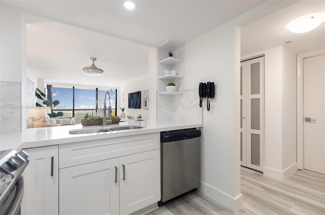 kitchen with sink, white cabinetry, light wood-type flooring, appliances with stainless steel finishes, and decorative backsplash