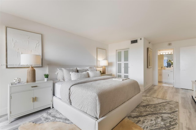 bedroom featuring ensuite bathroom and light wood-type flooring