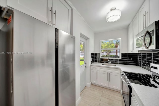 kitchen featuring sink, tasteful backsplash, light tile patterned floors, appliances with stainless steel finishes, and white cabinets