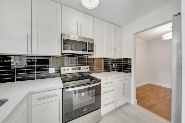 kitchen with white cabinetry, backsplash, stainless steel appliances, light stone counters, and light hardwood / wood-style floors