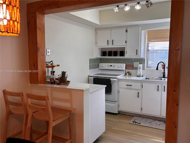 kitchen featuring electric stove, sink, white cabinetry, light hardwood / wood-style floors, and decorative backsplash