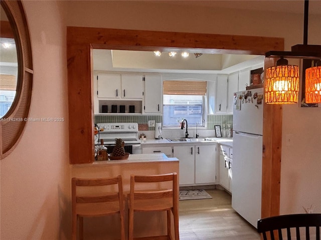 kitchen featuring white cabinetry, white appliances, a kitchen bar, and sink