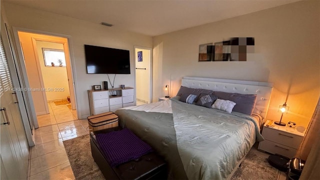 bedroom featuring ensuite bathroom and light tile patterned flooring