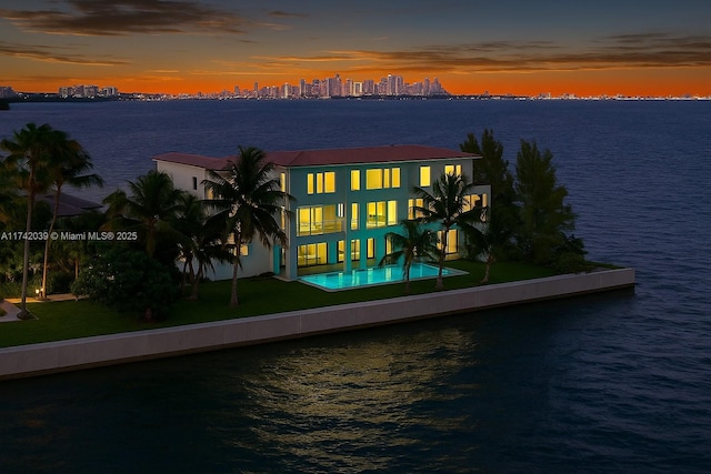 650 Lugo Ave, Coral Gables, FL 33156 - back of property at dusk with stucco siding, a yard, a water view, and a balcony