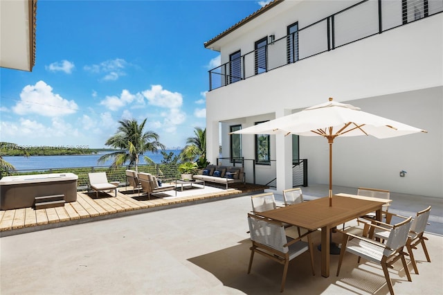 view of patio with outdoor dining space, a hot tub, a balcony, and a water view