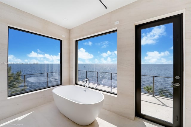 bathroom featuring a wealth of natural light, a soaking tub, and a water view