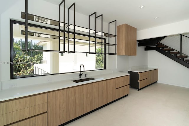 kitchen featuring light countertops, modern cabinets, light floors, and a sink