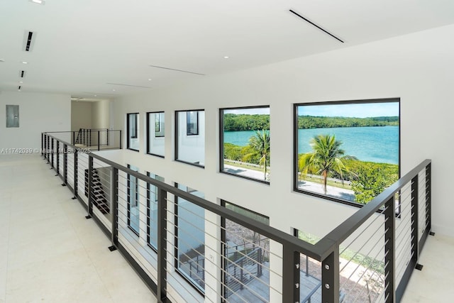 hall featuring electric panel, an upstairs landing, a water view, and light tile patterned flooring