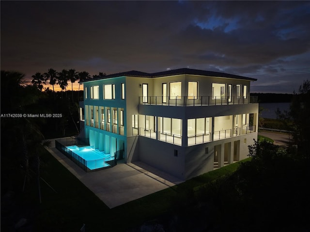 back of house featuring stucco siding and a balcony