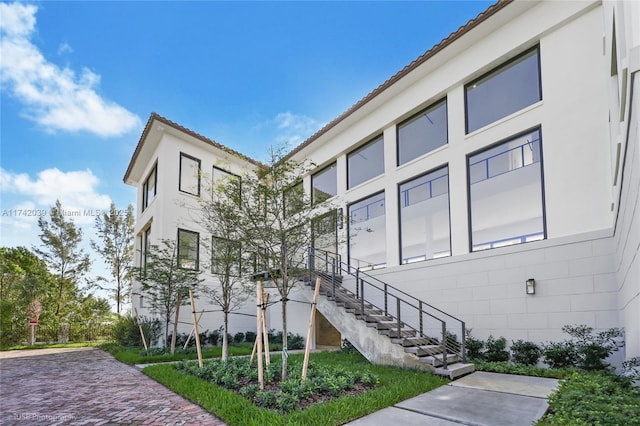 view of home's exterior featuring stairway, a tiled roof, and stucco siding