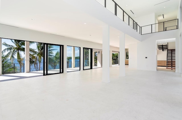 unfurnished living room featuring stairs and a high ceiling