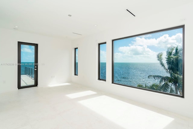 spare room with visible vents, a healthy amount of sunlight, and a water view