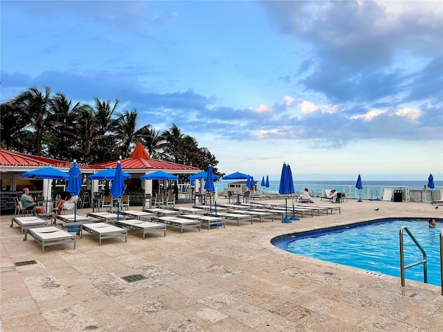 view of swimming pool featuring a patio and a water view