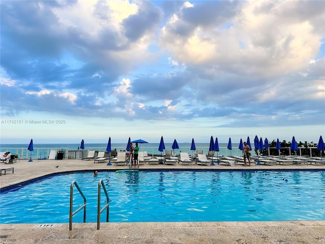 view of swimming pool featuring a water view and a patio area