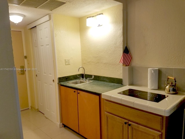 kitchen with light tile patterned flooring, sink, and black electric stovetop