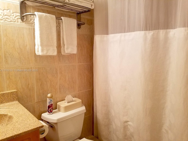 bathroom featuring vanity, tile walls, and toilet