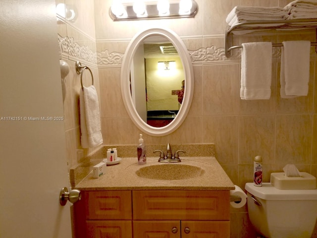 bathroom featuring vanity, tile walls, and toilet