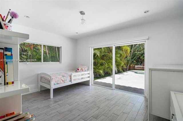 bedroom featuring access to exterior, multiple windows, and wood finished floors