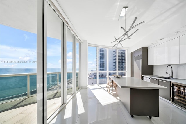 kitchen featuring beverage cooler, modern cabinets, floor to ceiling windows, light countertops, and white cabinetry