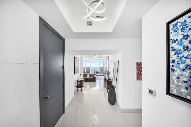 corridor featuring light tile patterned floors, baseboards, and visible vents